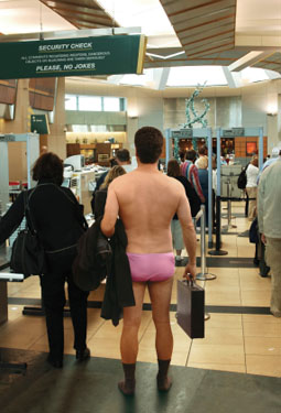Man at airport security, having removed everything but his pink underwear and socks
